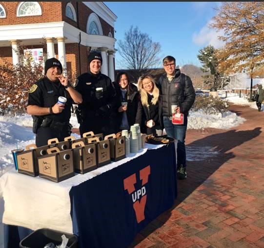 UVA police officers and students stand at a table with coffee containers and trays of cookies